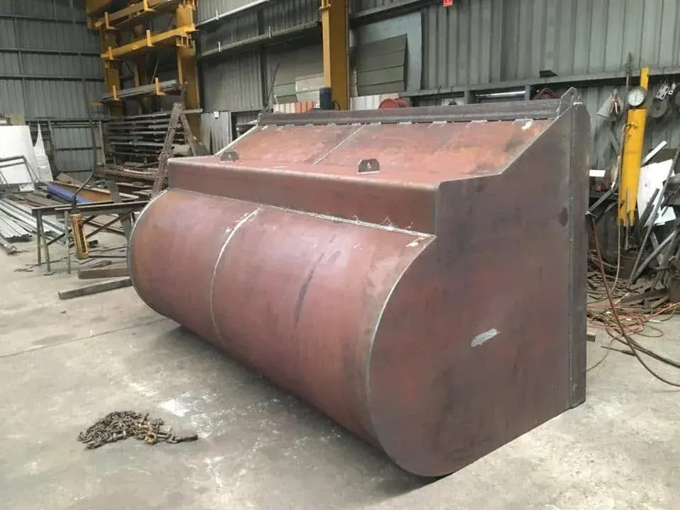 Excavator bucket in red oxide primer on the workshop floor after repair
